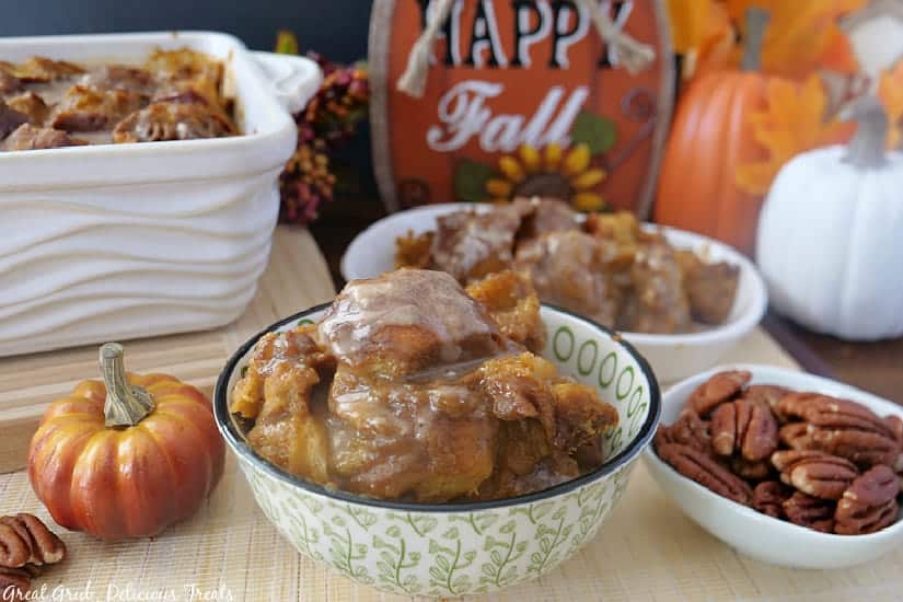Pumpkin pecan bread pudding in a couple white bowls with the baking dish in the background with fall foliage in the photos.