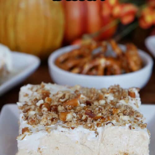 A white plate with a slice of pumpkin pretzel dessert on it.