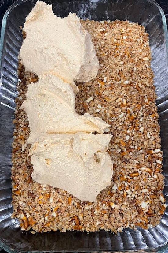 A glass baking dish with the baked pretzel crust and the pumpkin filling spooned on top.