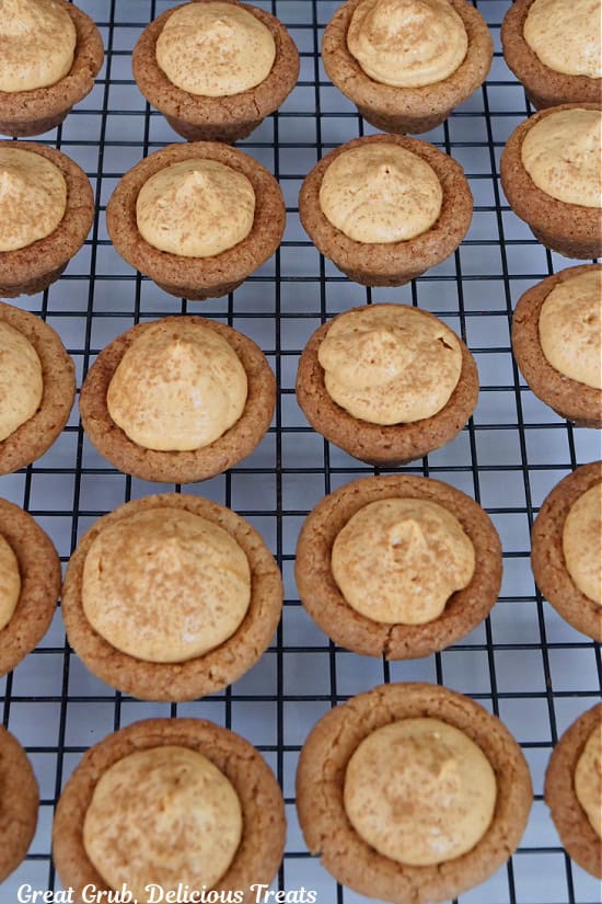 A wire rack with approximately 20 pumpkin spice cookie bites on it.