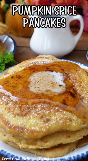 Three fluffy pancakes on a white plate with blue trim.