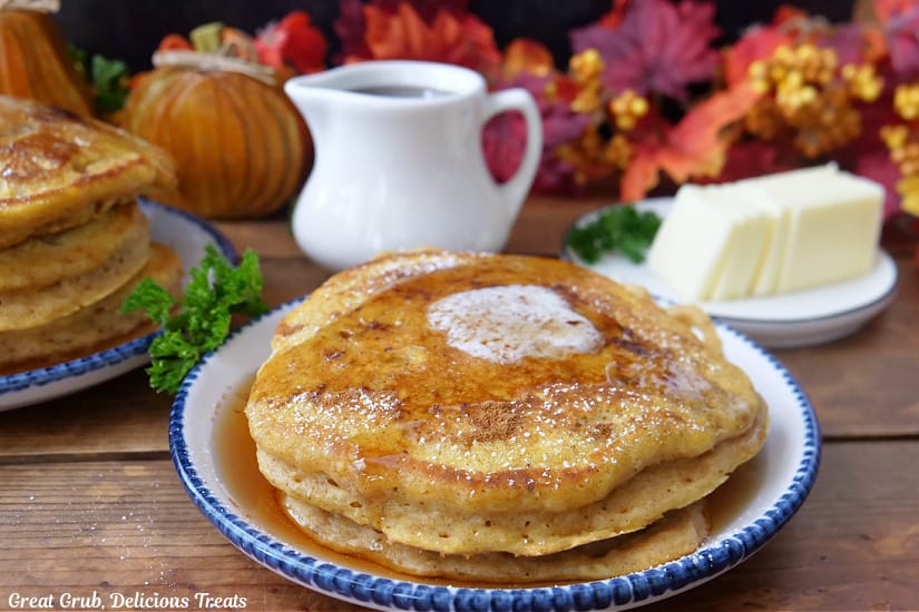 A horizontal photo of a white plate with a small stack of pancakes on it.