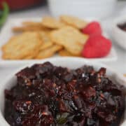 A round white bowl with raspberry jalapeno bacon jam in it with the title overlay at the top.