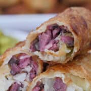 A small stack of Reuben egg rolls stacked on top of each other showing the inside ingredients.