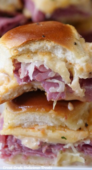 Two Reuben sliders stacked on top of each other with a bite taken out of the top slider.