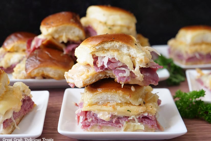 A horizontal photo of Reuben sliders on white plates.