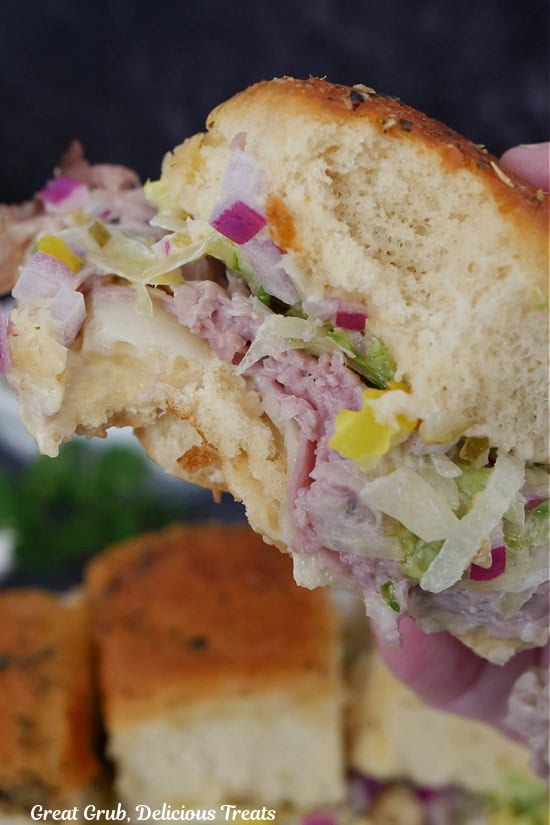 A roast beef slider with a bite taken out of it.