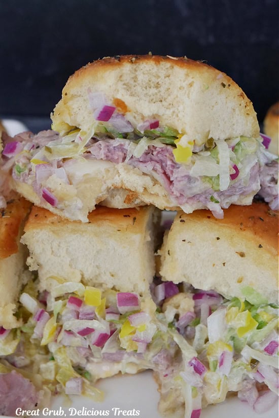 A small stack of roast beef sliders with a lettuce slaw with a bite taken out of the slider on top.