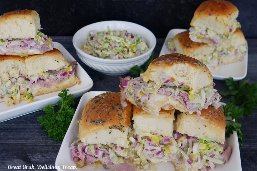Three white plates with roast beef sliders on them with a small white bowl filled with a tangy lettuce slaw.