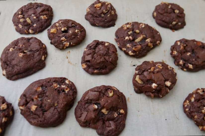A baking sheet with parchment paper with baked cookies on it.