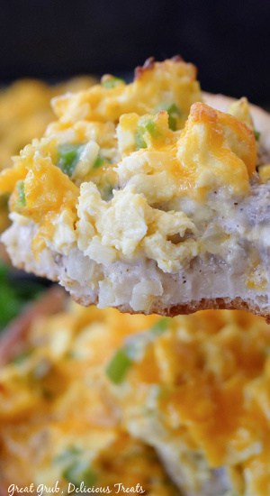 A close up of a bite taken out of a slice of breakfast pizza.