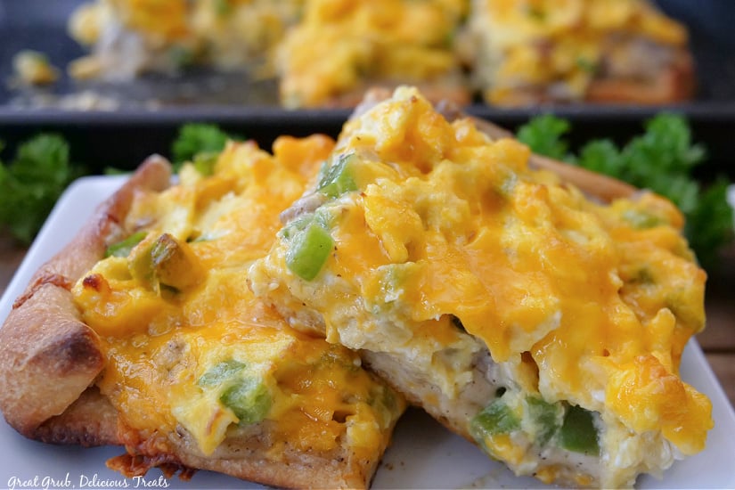 A horizontal photo of two slices of sausage breakfast pizza on a white plate.