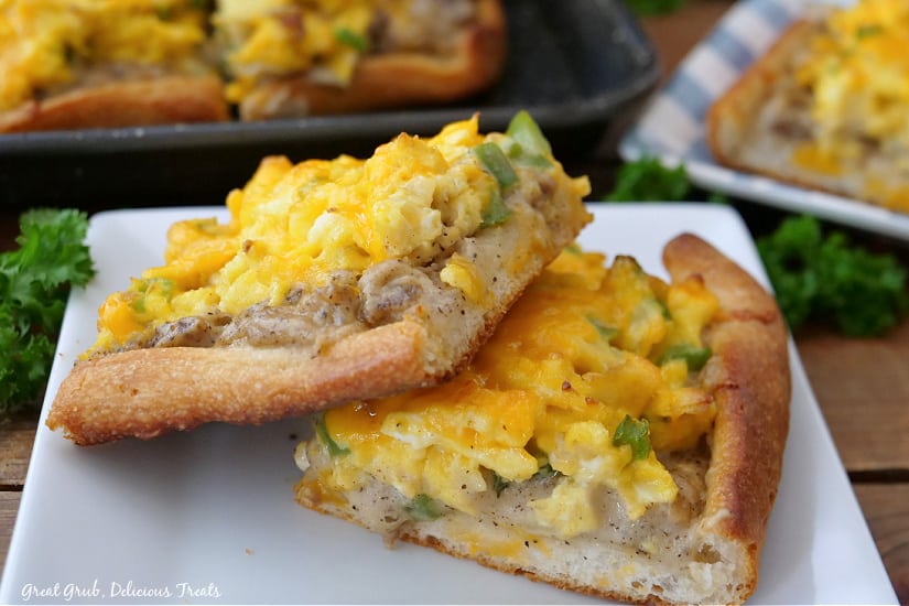 A white plate with two slices of breakfast pizza on it.