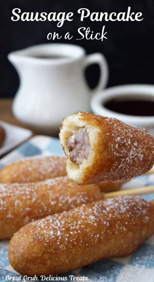 A pancake on a stick with sausage and a bite taken out of it.