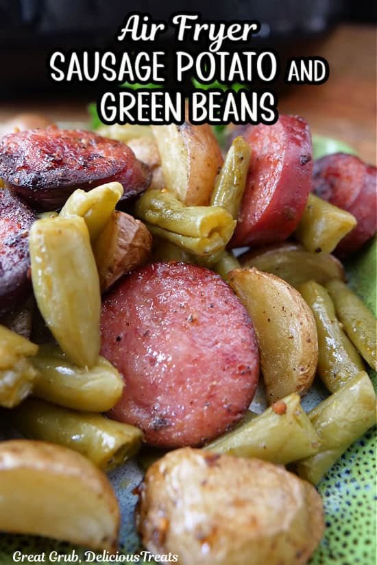 A green plate with a serving of sausage potatoes and green beans made in the air fryer.