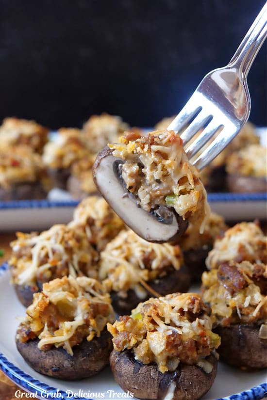 A stuffed mushroom on a fork that has been cut in half showing the inside ingredients.
