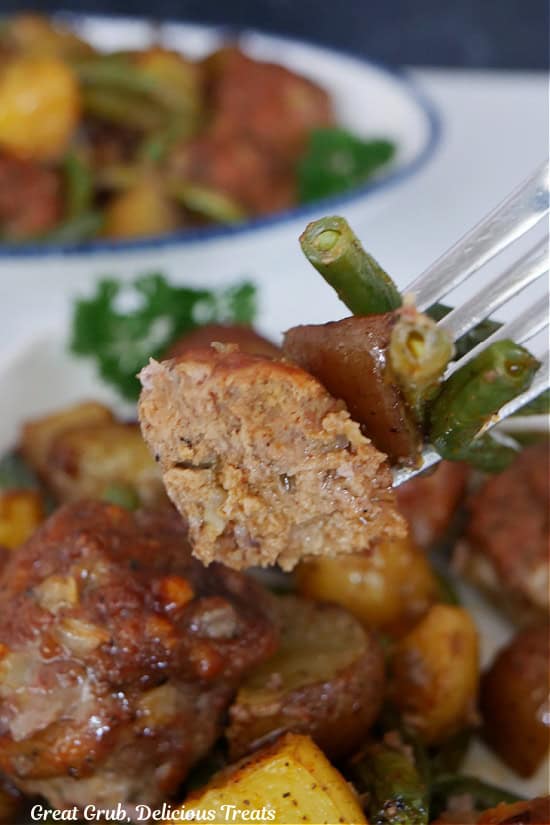 A bite of meatball, potato and green beans on a fork.