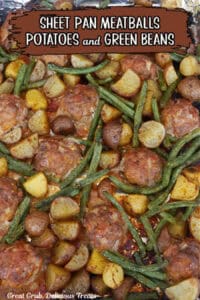 A baking sheet with homemade meatballs, potatoes, and green beans on it.