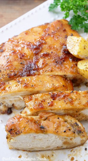 Cut chicken breast on a white plate with potatoes and parsley on the plate as well.