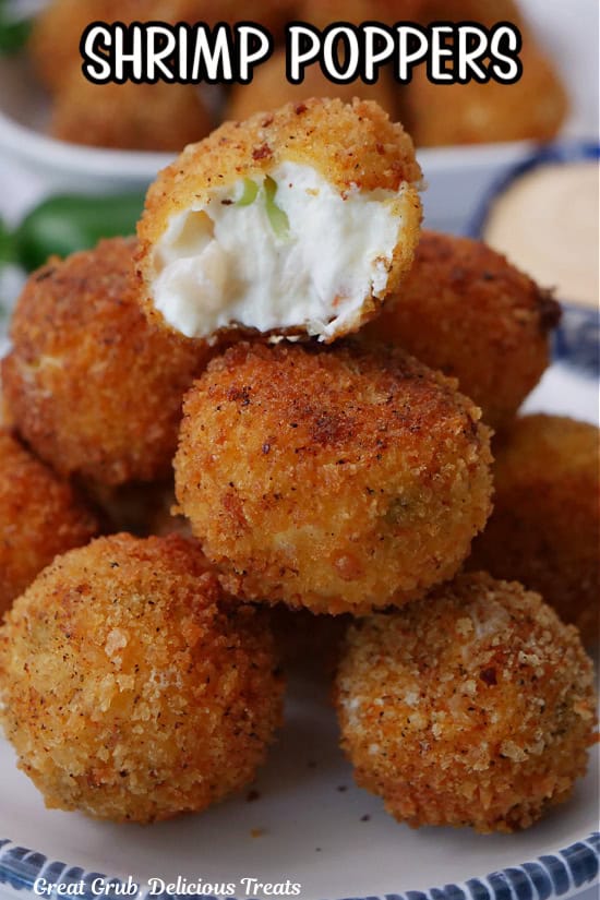 A small round white plate with blue trim with a stack of shrimp poppers on it with a bite out of the popper on top.