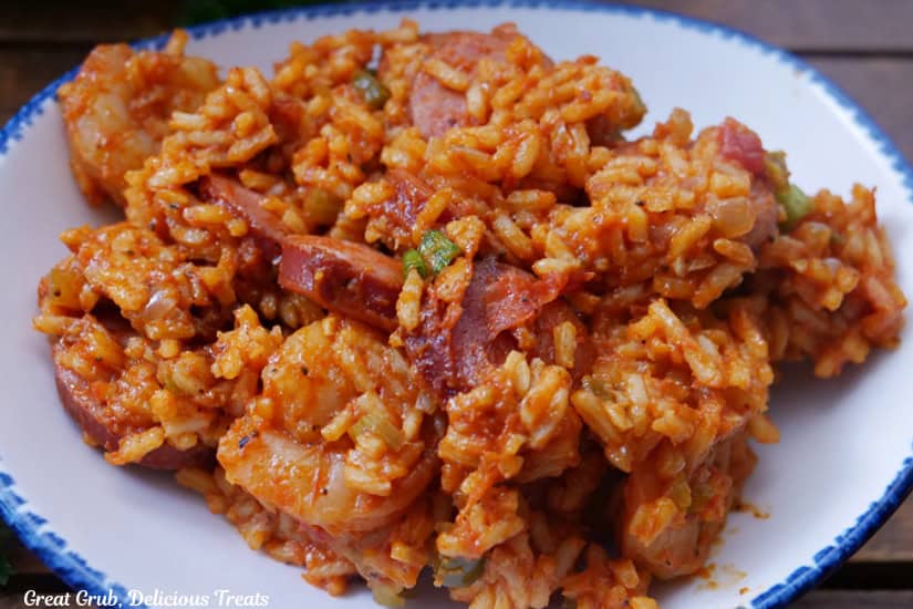 A white oval bowl with blue trim filled with shrimp and sausage jambalaya.