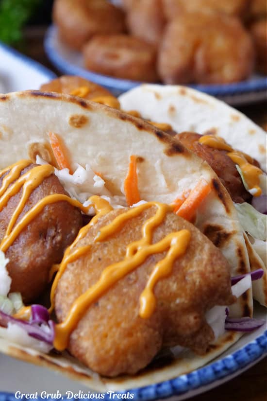 A fried shrimp taco in a flour tortilla with sauce drizzled over the shrimp.