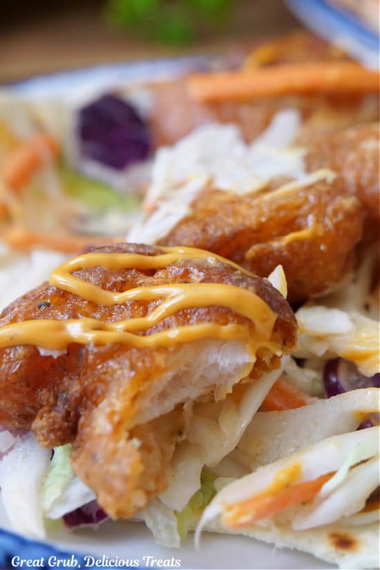 A flour tortilla with fried, crispy shrimp and a bite taken out of it.