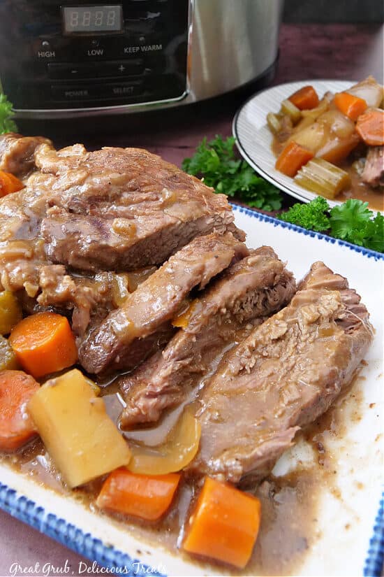 Roast, carrots, potatoes on a white plate with blue trim.