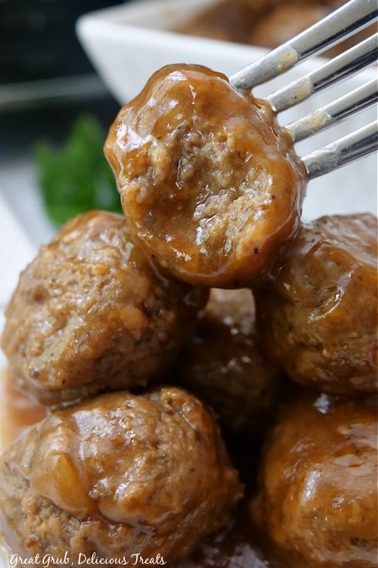 Meatballs stacked up on a plate with a bite taken out of the top meatball.
