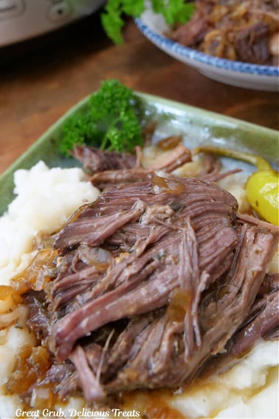 A green square plate with mashed potatoes and pot roast on it.
