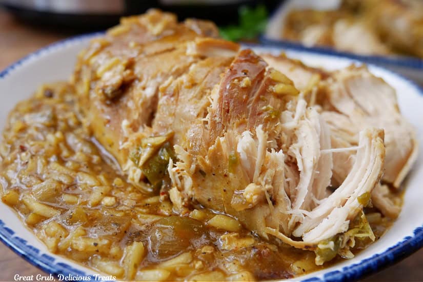 A white plate with blue trim with chicken and rice on it.