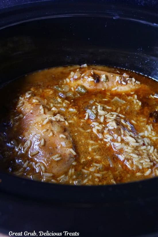 A crock pot with the chicken and rice in it after it has slow cooked.