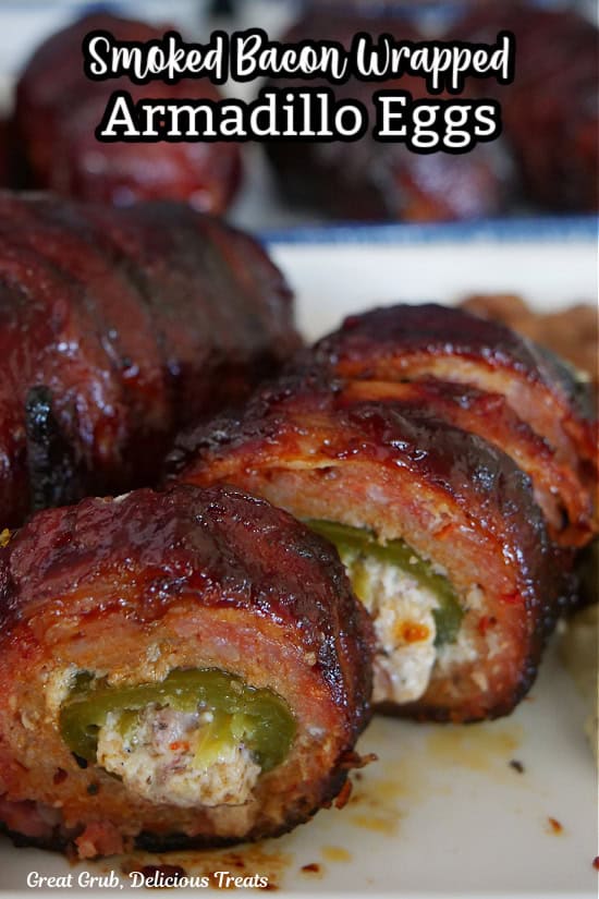 A white plate with two bacon wrapped armadillo eggs on it with one that has been sliced into bite size pieces.