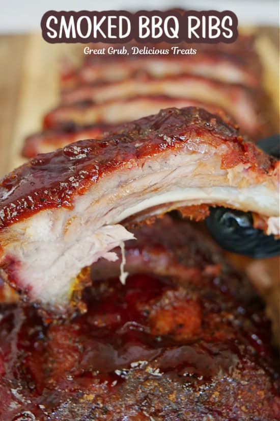 A smoked pork ribs held above the rack of ribs below.