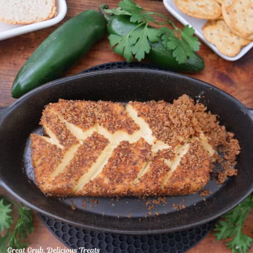 A wood surface with a black oval dish with a smoked cream cheese in it.