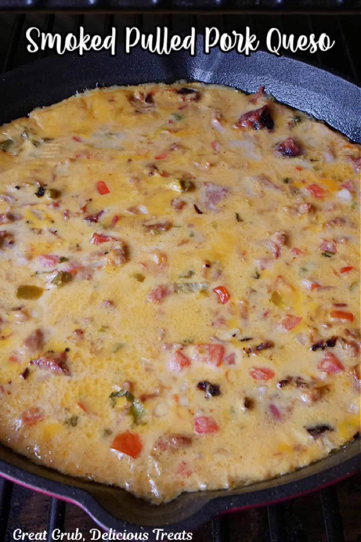 A red and black cast iron pan with smoked pulled pork queso in it after being smoked.
