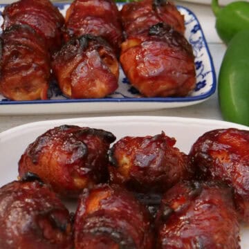 Two white plates on a white surface with bite-size, bacon wrapped shotgun shell bites on them.