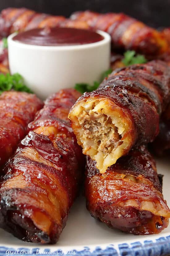 A close up of a few stuffed manicotti shotgun shells with a bite taken out of one of them.