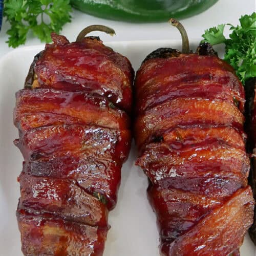 Two smoked bacon wrapped stuffed poblano peppers on a white plate with the title in text at the top.