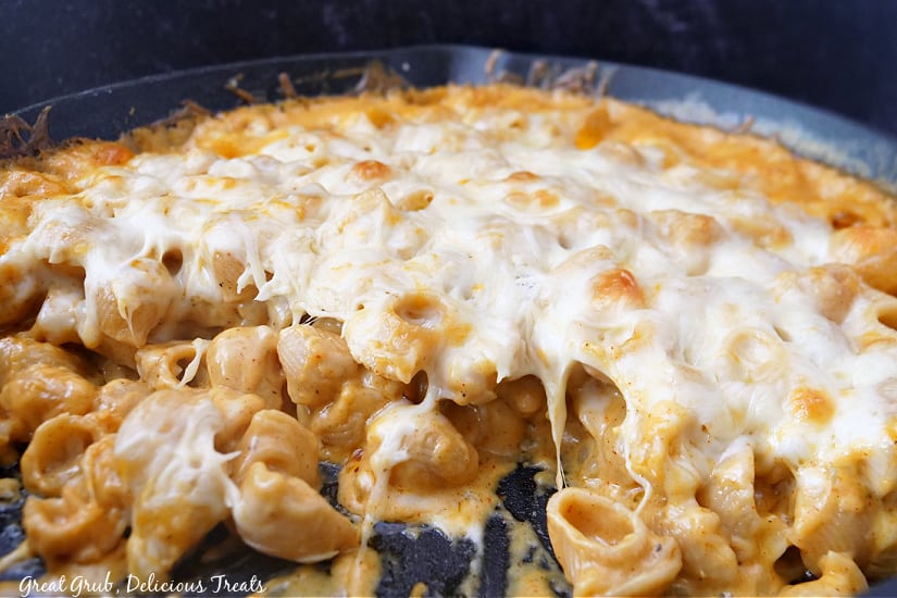 Smoked Mac and Cheese is a cheesy, creamy, and delicious mac and cheese that is cooked in a cast iron and topped with even more cheese. A cast iron skillet with mac and cheese covered in cheese.