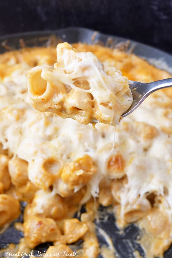 Smoked Mac and Cheese is a delicious recipe that would make a great side dish for any of your favorite meals. A bite of mac and cheese hovering over the cast iron filled with mac and cheese.