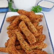 A white oblong plate with blue trim with a serving of spicy green beans on it.