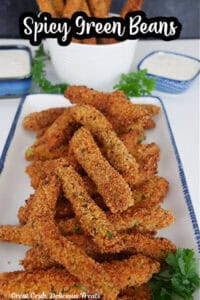 A white oblong plate with blue trim with a serving of spicy green beans on it.