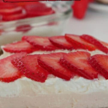 A white plate with blue trim with a slice of strawberry pretzel dessert on it with fresh strawberries in the background.