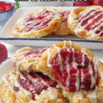 Two white plates with blue trim with strawberry danishes on them.