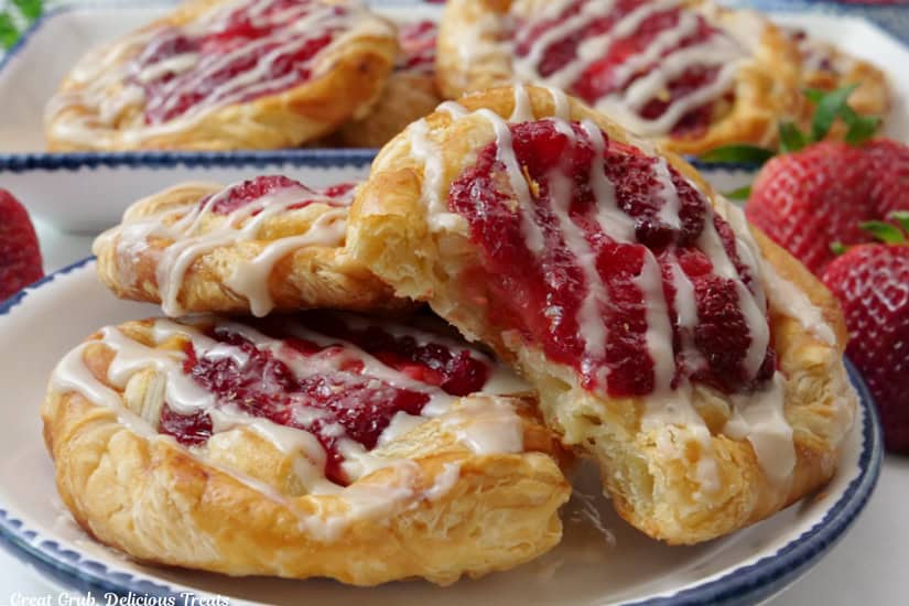 A horizontal photo of strawberry danishes on a two white plates with blue trim.