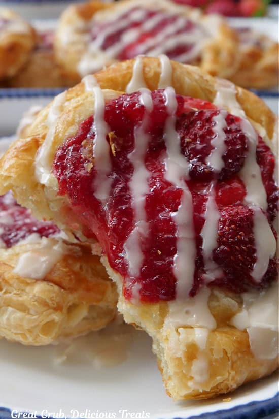A close up of a strawberry danish with a couple bites taken out of it.