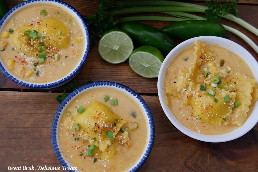 Three soup bowls on a wood surface filled with street corn ravioli soup.