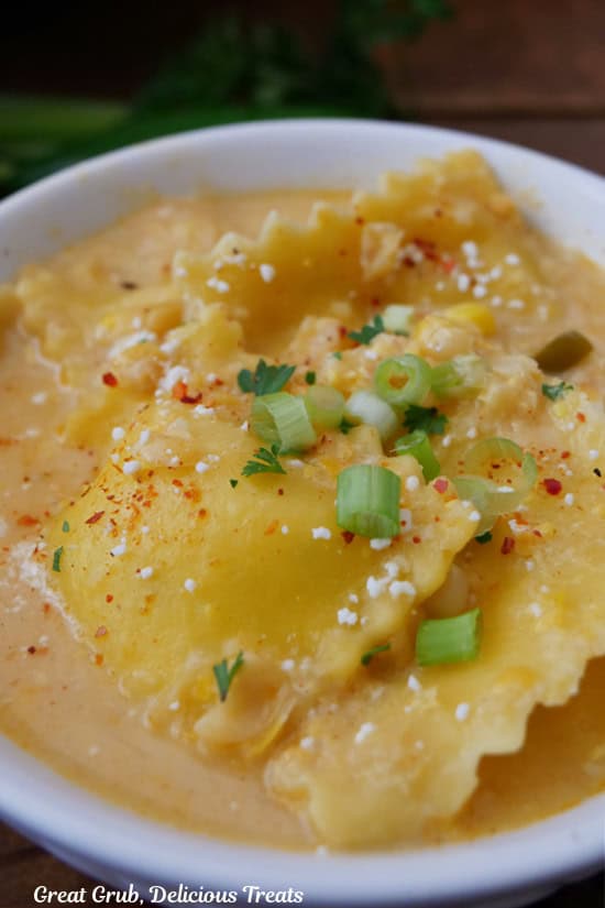 A serving of street corn ravioli soup in a white bowl.