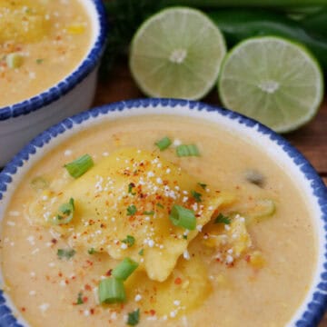 A white bowl with blue trim filled with street corn ravioli soup.